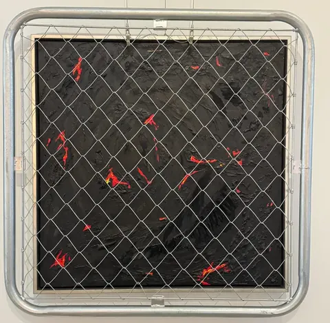 溶岩のような赤い亀裂の黒い画面に本物の金網フェンスを組み合わせた作品